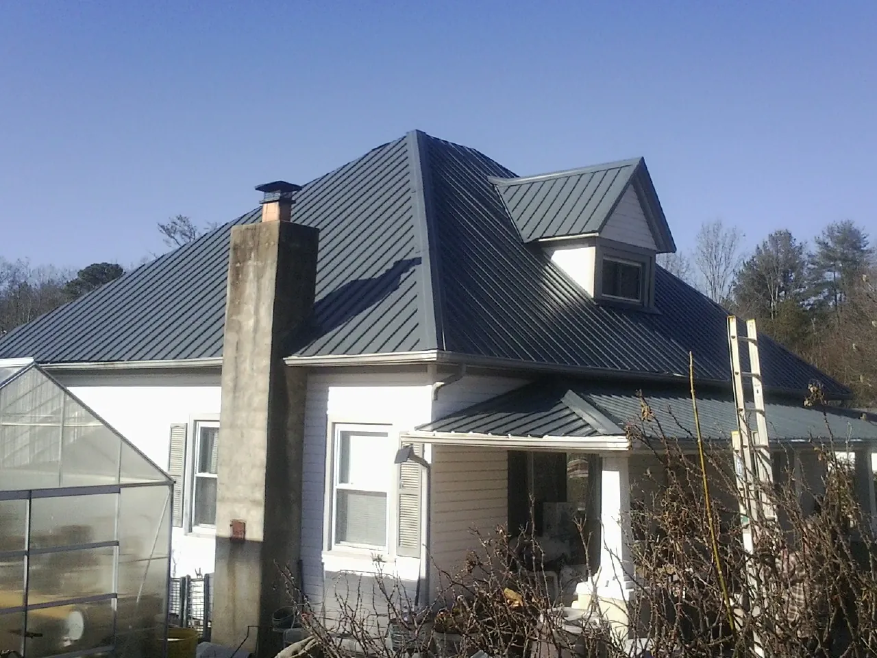 Dark blue standing seam metal roof on a white farmhouse with dormer — Slate & Tile Roof Repair by Roofing Brothers in North Middletown