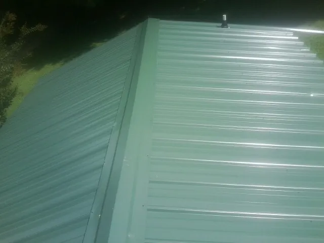 New green metal panels meeting at the ridge of a roof — Flat Roof Repair work by our crew in North Middletown