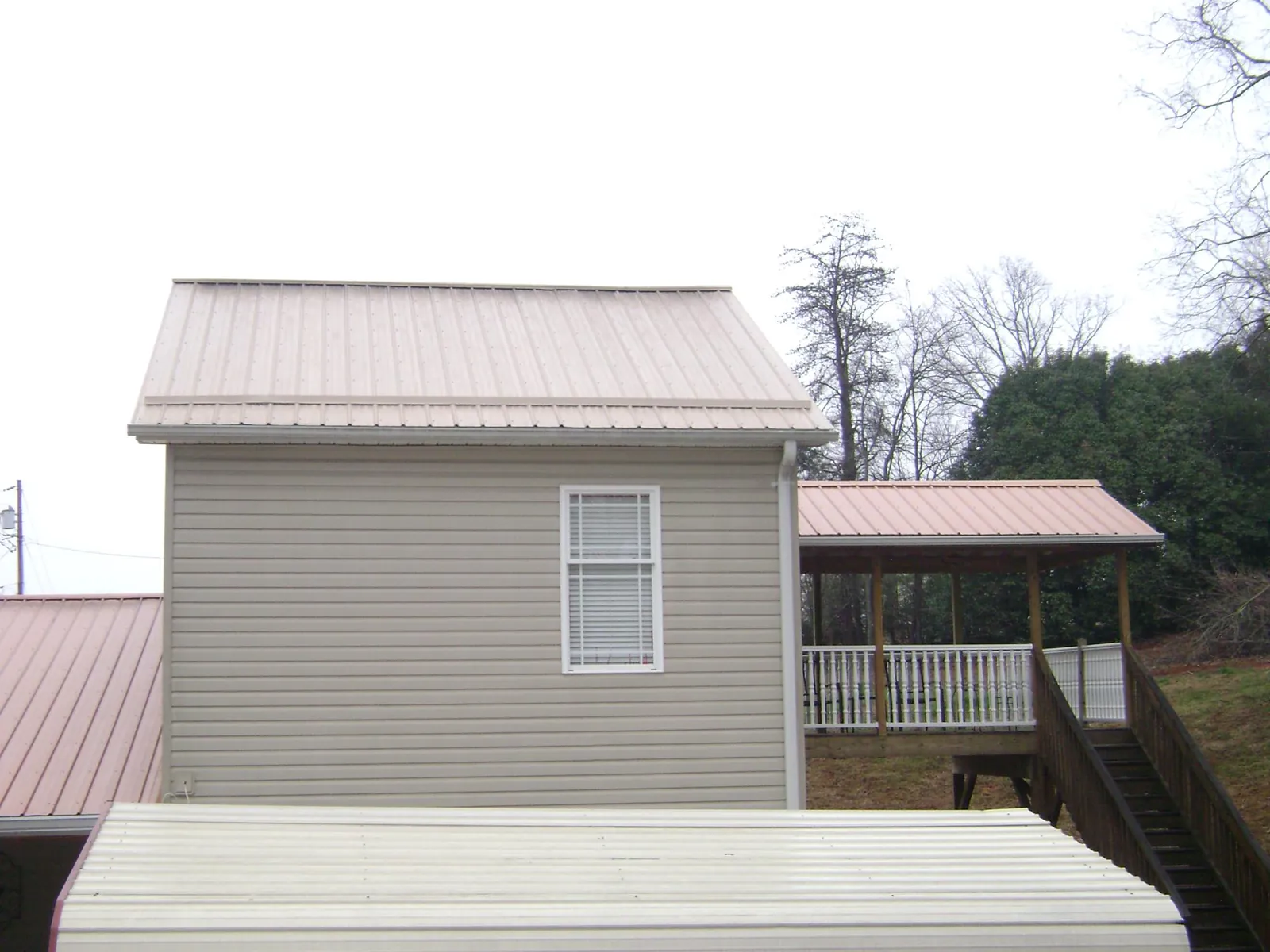 Tan metal roofs on a two story addition and attached porch, from a Roof Replacement job in North Middletown