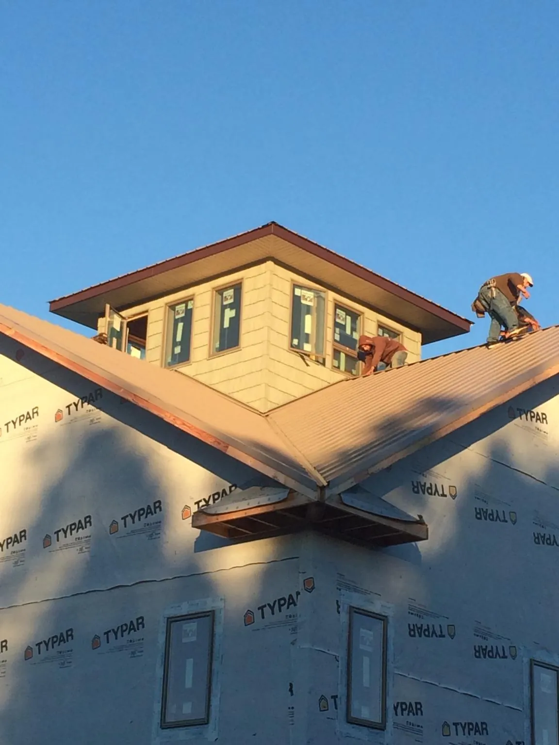 Roofers working around a rooftop cupola on a new metal roof at sunset — Roof Waterproofing in North Middletown by Roofing Brothers